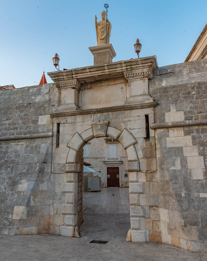 View of the historic North Town Gate in Trogir, Croatia. This medieval stone gateway with arched entrance served as a crucial defensive point and controlled access to the town during the medieval period. 
